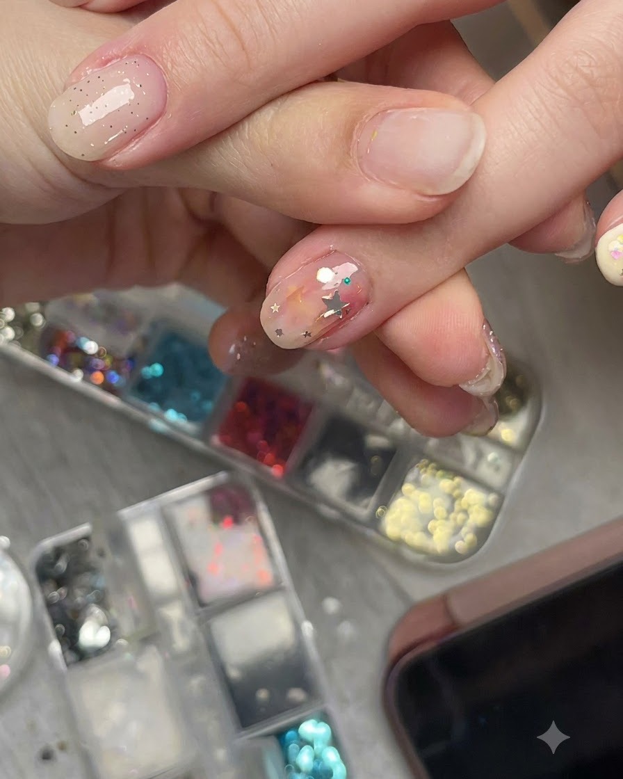 A close-up shot of a hand viewing a pre-curved star glitter piece on a nail from a side angle to show its flush fit.