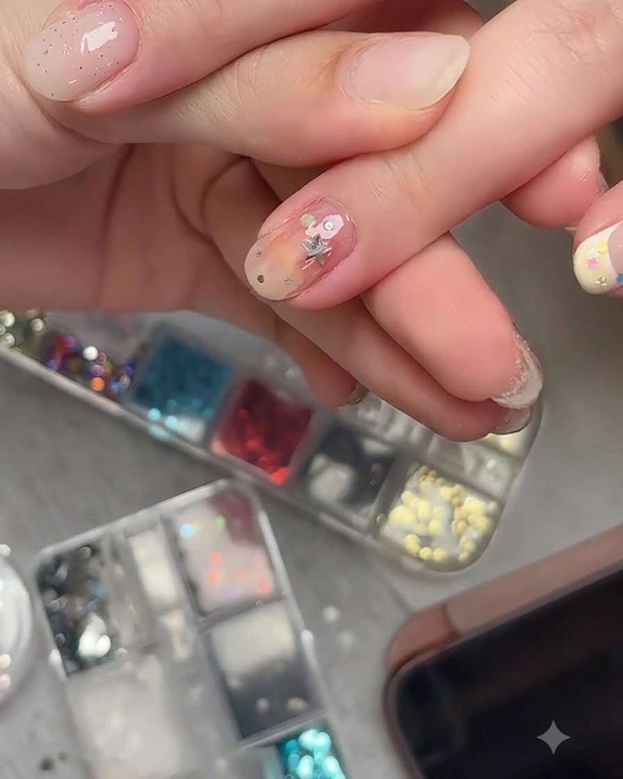 A nail art brush applying a clear top coat over embedded star glitter pieces on a finished nail.