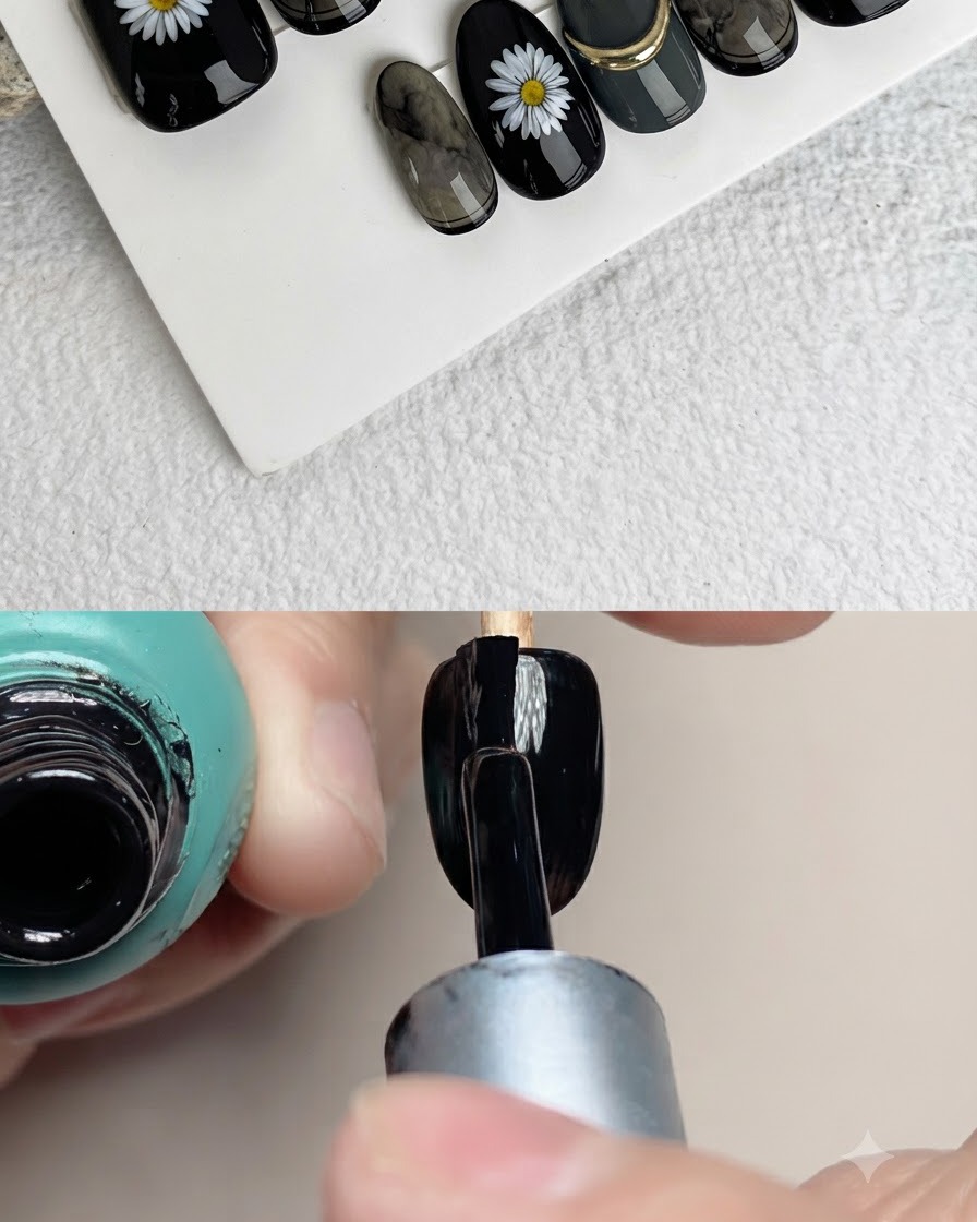 A close-up of a nail brush painting white petals on a black artificial nail surface.
