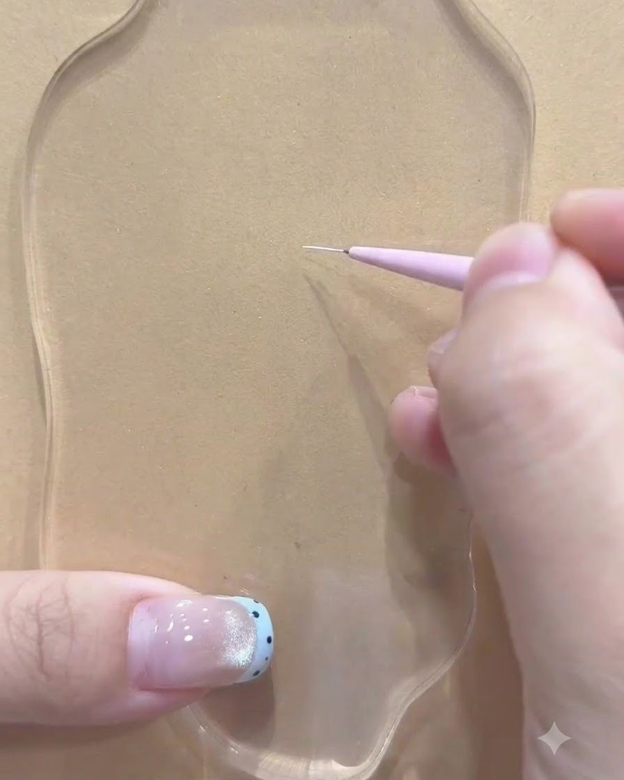 A fine liner brush held by a hand making the first white stroke on a clear palette.