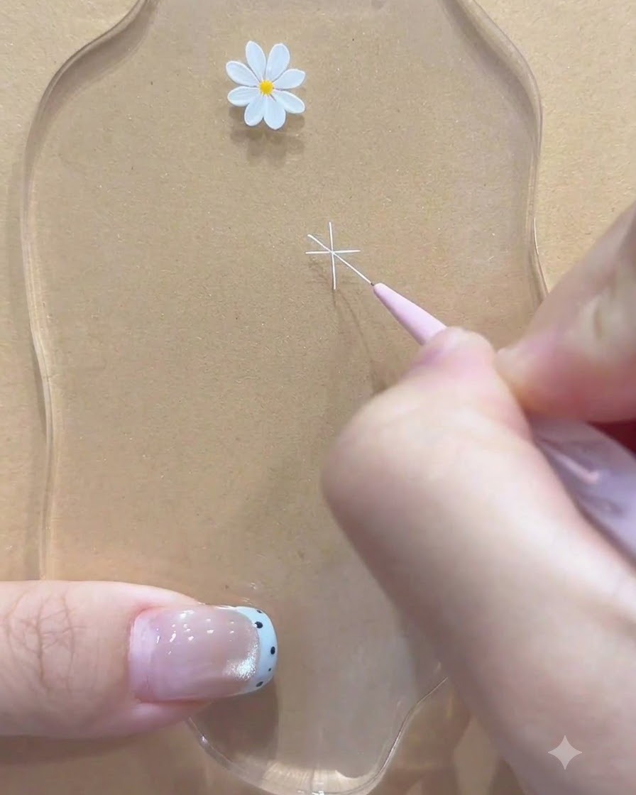 A fine liner brush adding extra diagonal white lines to complete the daisy flower outline.