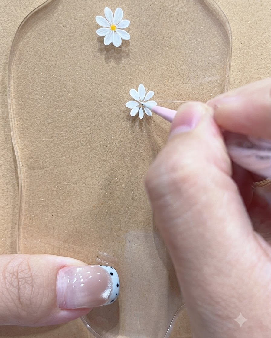 A fine liner brush drawing delicate petals for a smaller daisy motif on a palette.