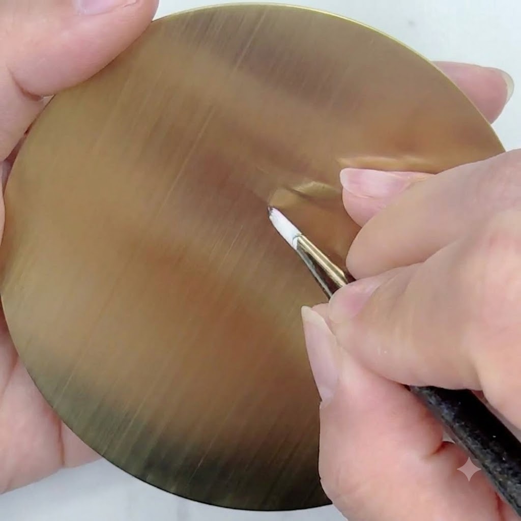A fine liner brush with white gel drawing straight, thin guide lines radiating from a central point on a golden circular practice palette.