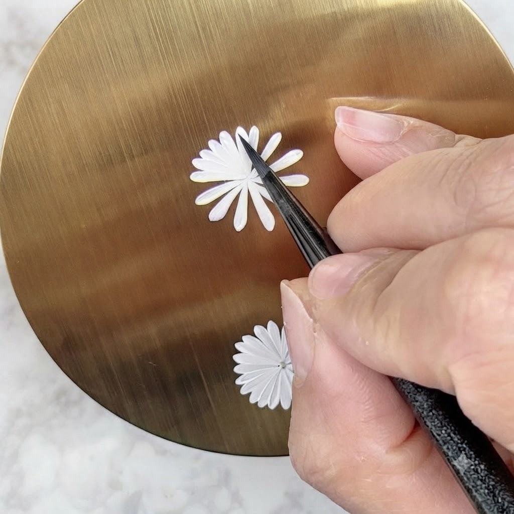 A nail art brush carefully painting a second, smaller inner layer of white petals on a daisy design.
