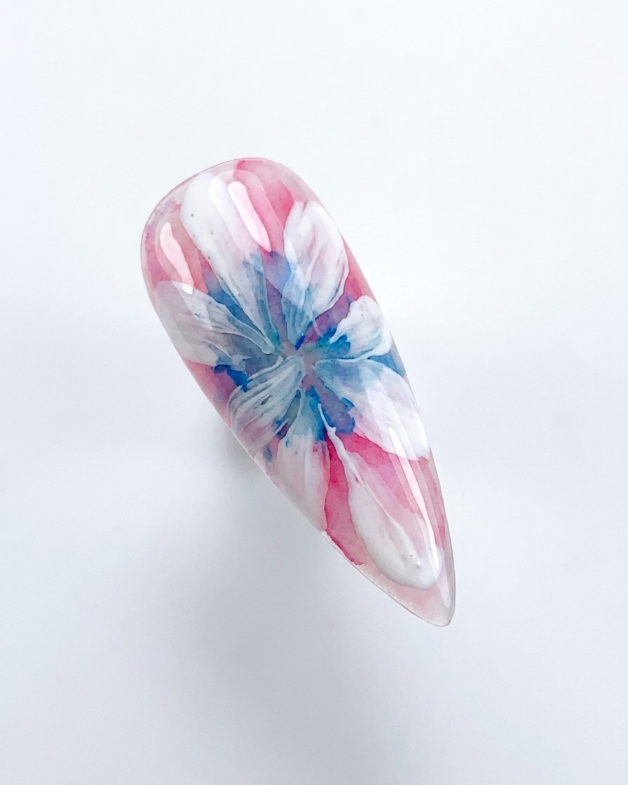 A hand placing a decorated nail under a pink UV/LED curing lamp.