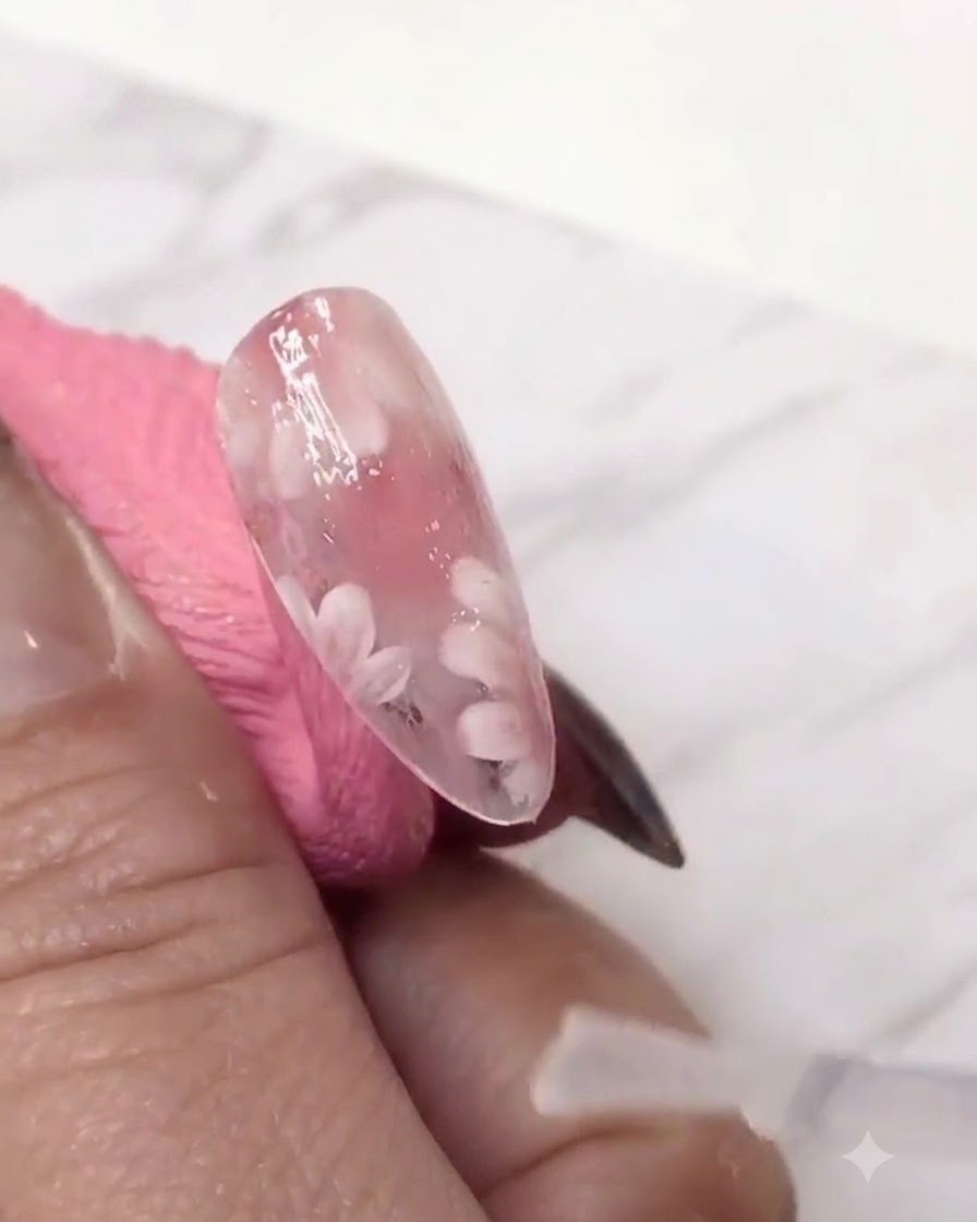 A fine liner brush adding a second layer of white daisy petals over the pink tinted gel layer for depth.