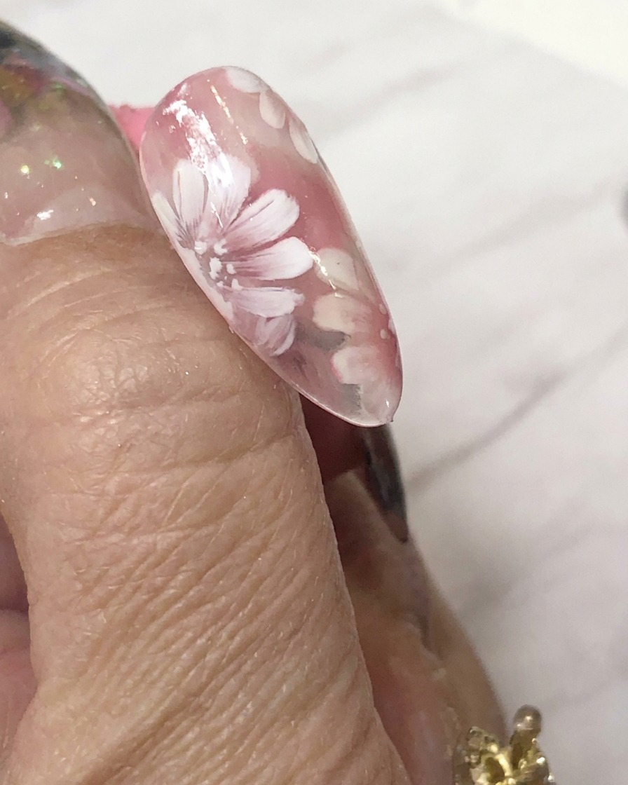 A mini LED curing lamp positioned directly over a decorated nail to cure the gel art.