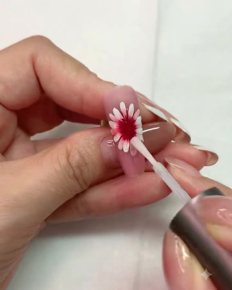 A fine brush painting a textured white circular base with small gaps in the center of the daisy.