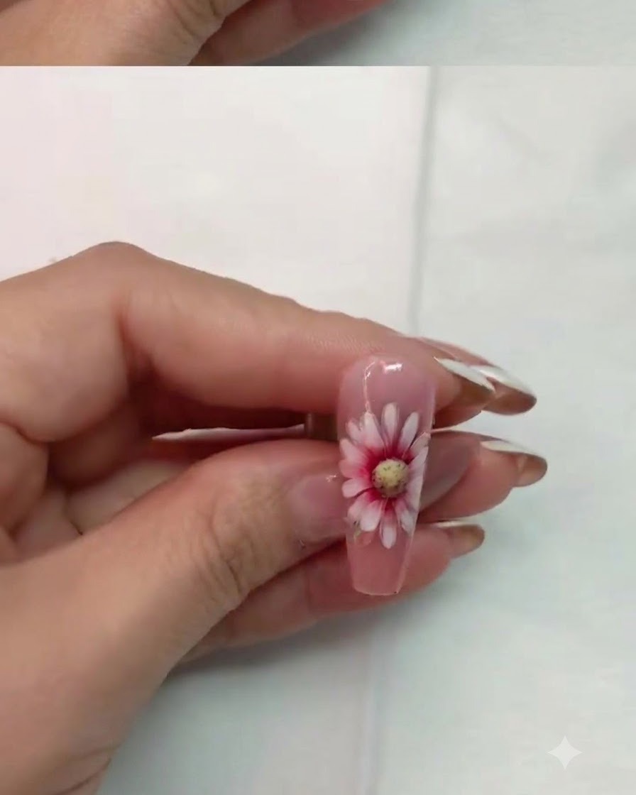 A nail with completed double-layer daisy art curing under an LED lamp.
