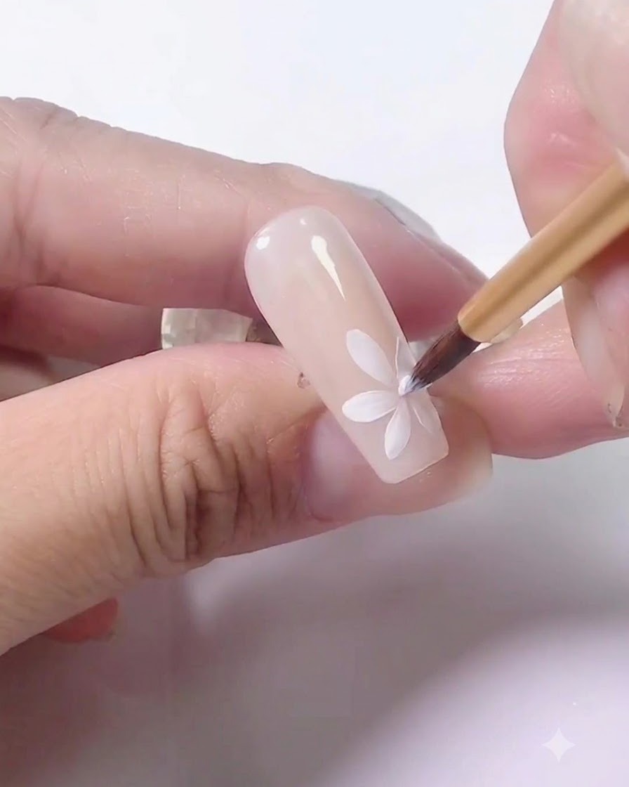 A hand placing a practice nail under a UV lamp for curing.