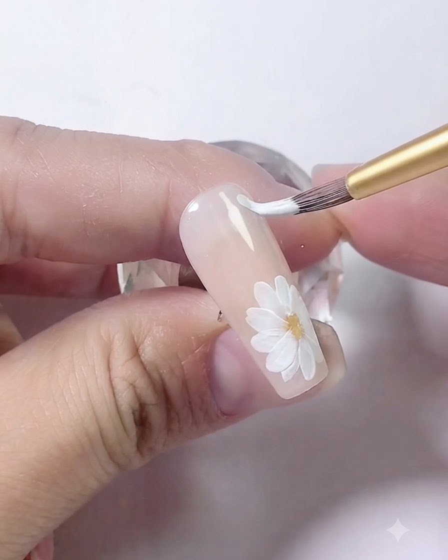 A nail art brush drawing two parallel curved white lines along the edge of the nail.