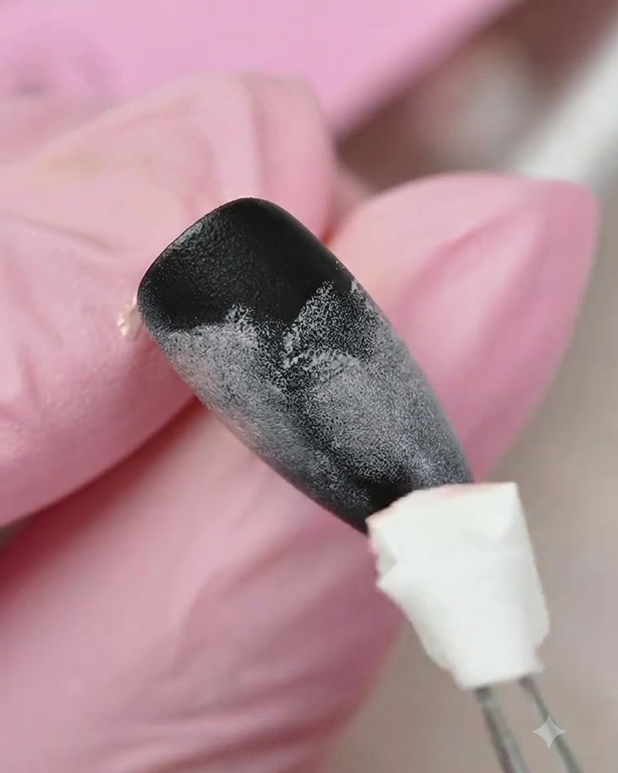 A sponge applicator dabbing yellow gel onto the lower portion of a black and pink gradient-textured nail.