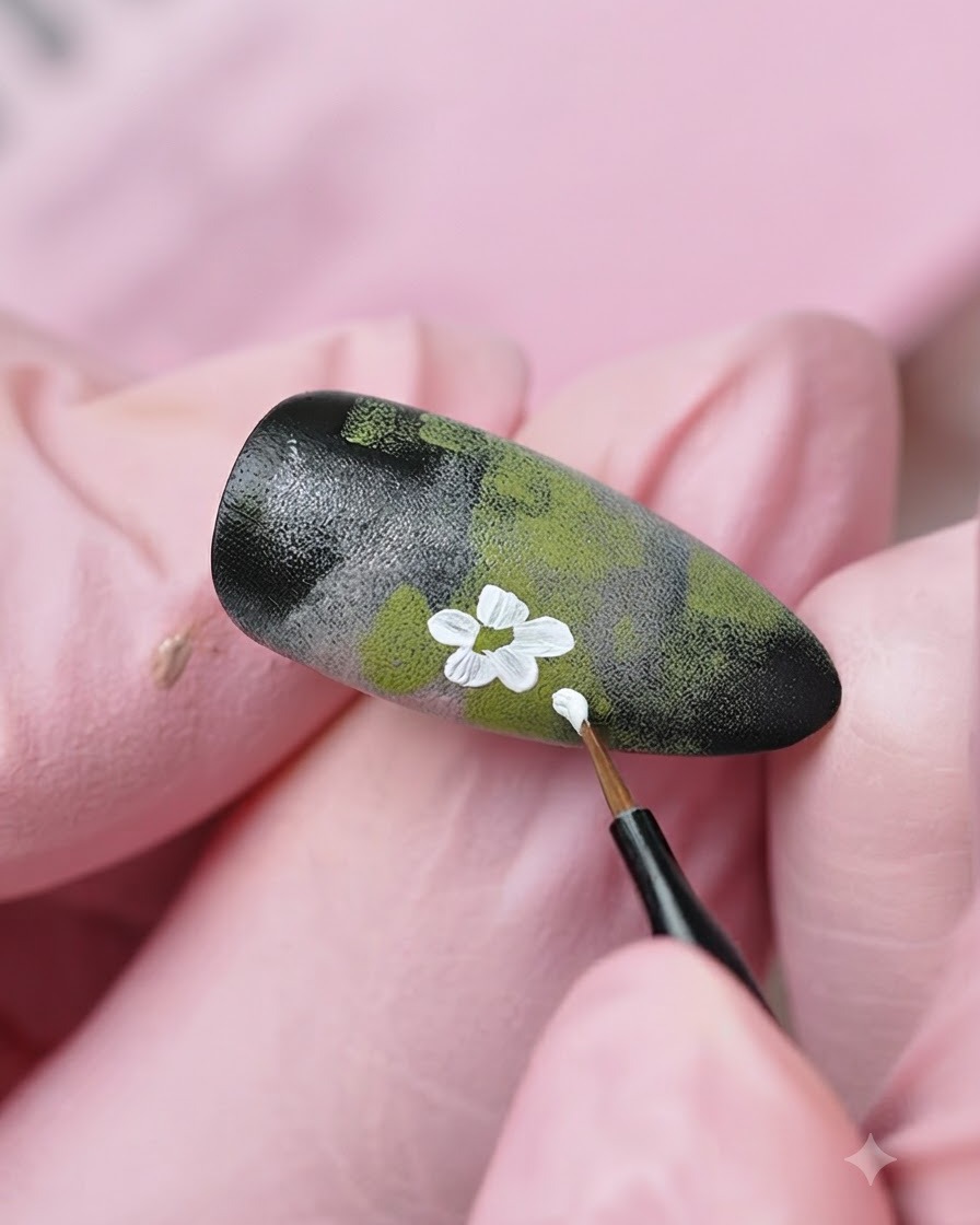 A fine liner brush adding more white flower details and buds onto the textured nail design.