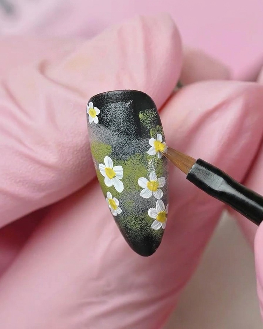 A flat brush smoothing a layer of translucent milky white gel polish over the nail surface.