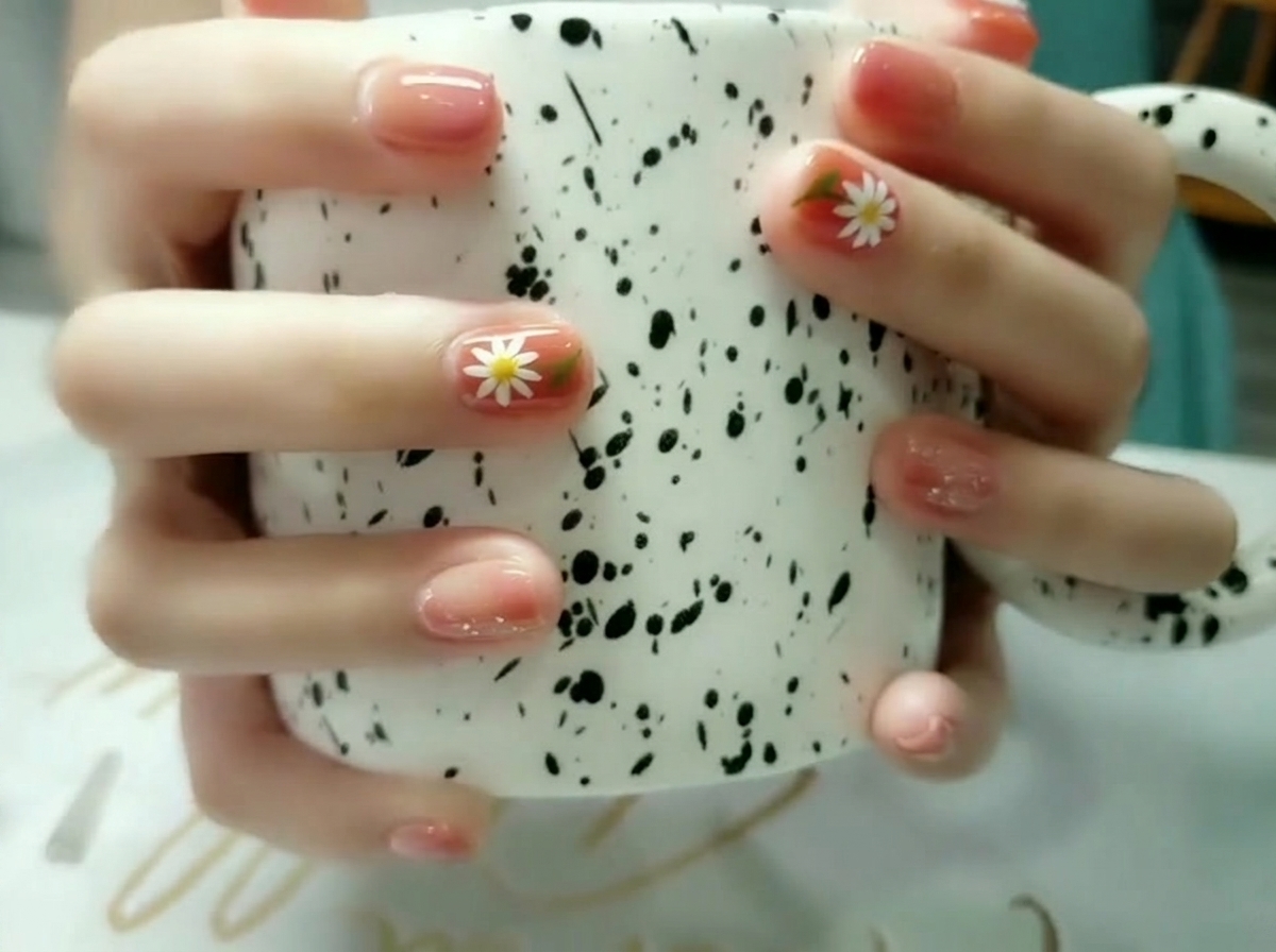 A close-up shot focusing on an accent nail featuring a hand-painted white daisy with a yellow center and green leaf.