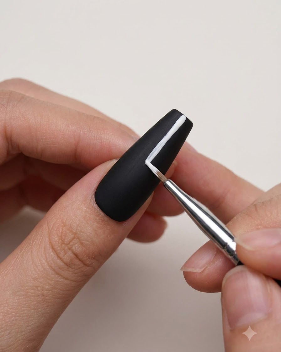 A fine detail brush applying white gel to create straight stroke lines on a matte black nail.