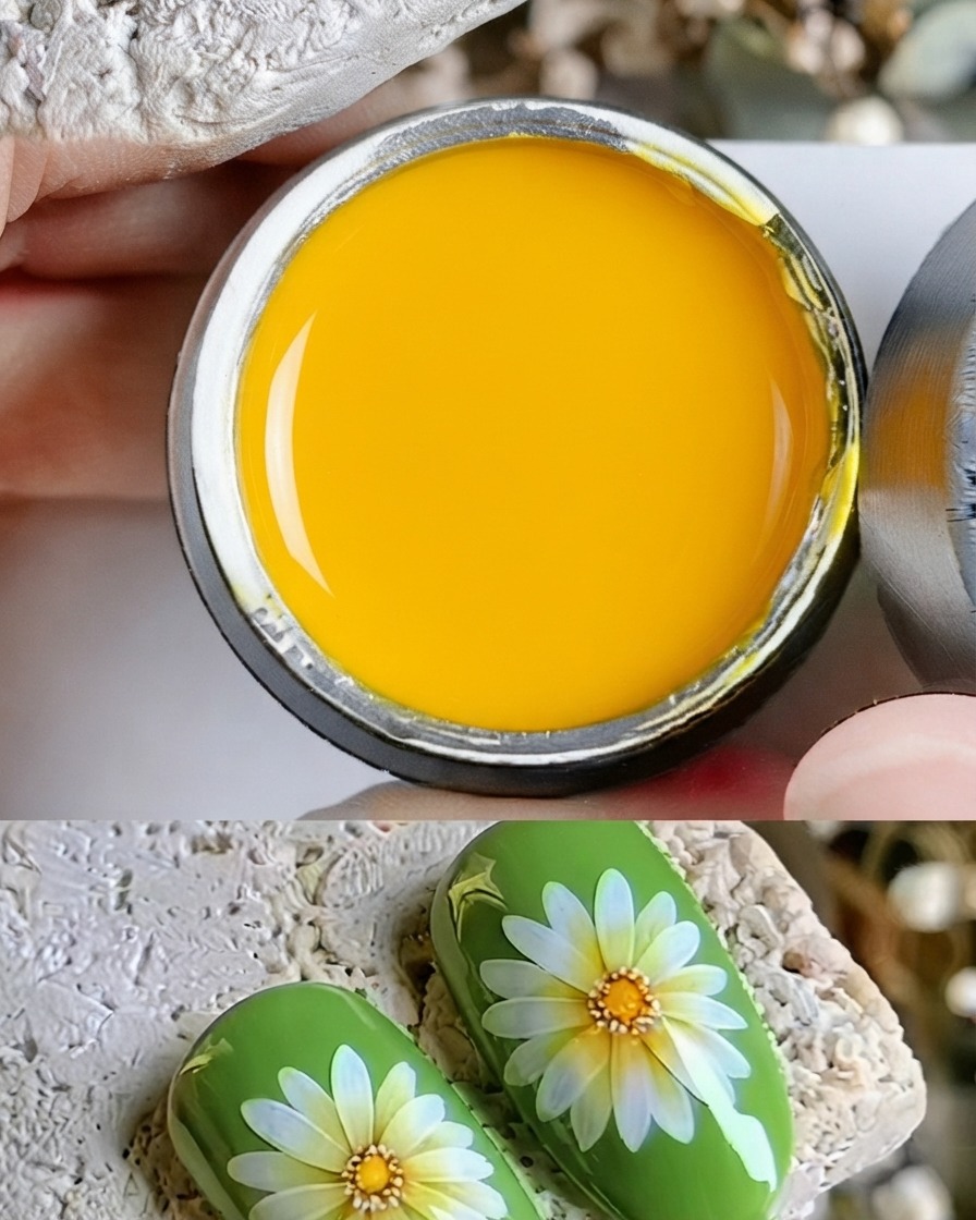 A close-up of a fine brush depositing a dot of yellow gel onto the center of a painted daisy.