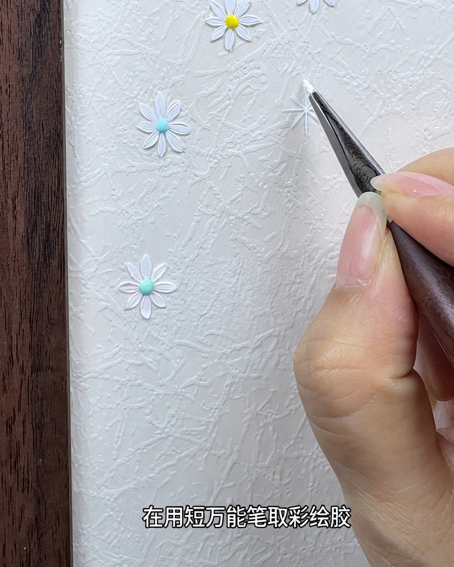 A hand holding a fine detail brush loaded with white painting gel near a textured background.