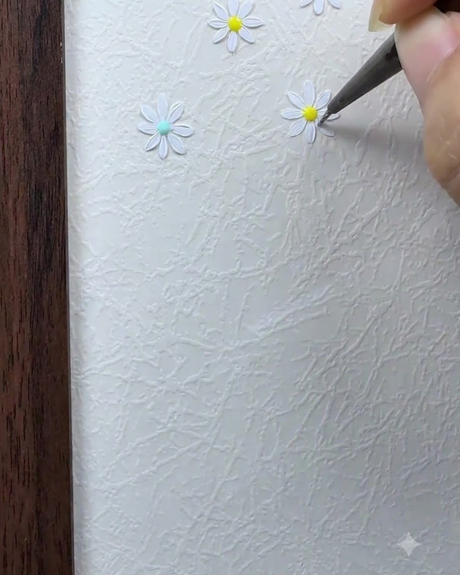 A fine brush filling in the remaining white petals around the center of the daisy flower.