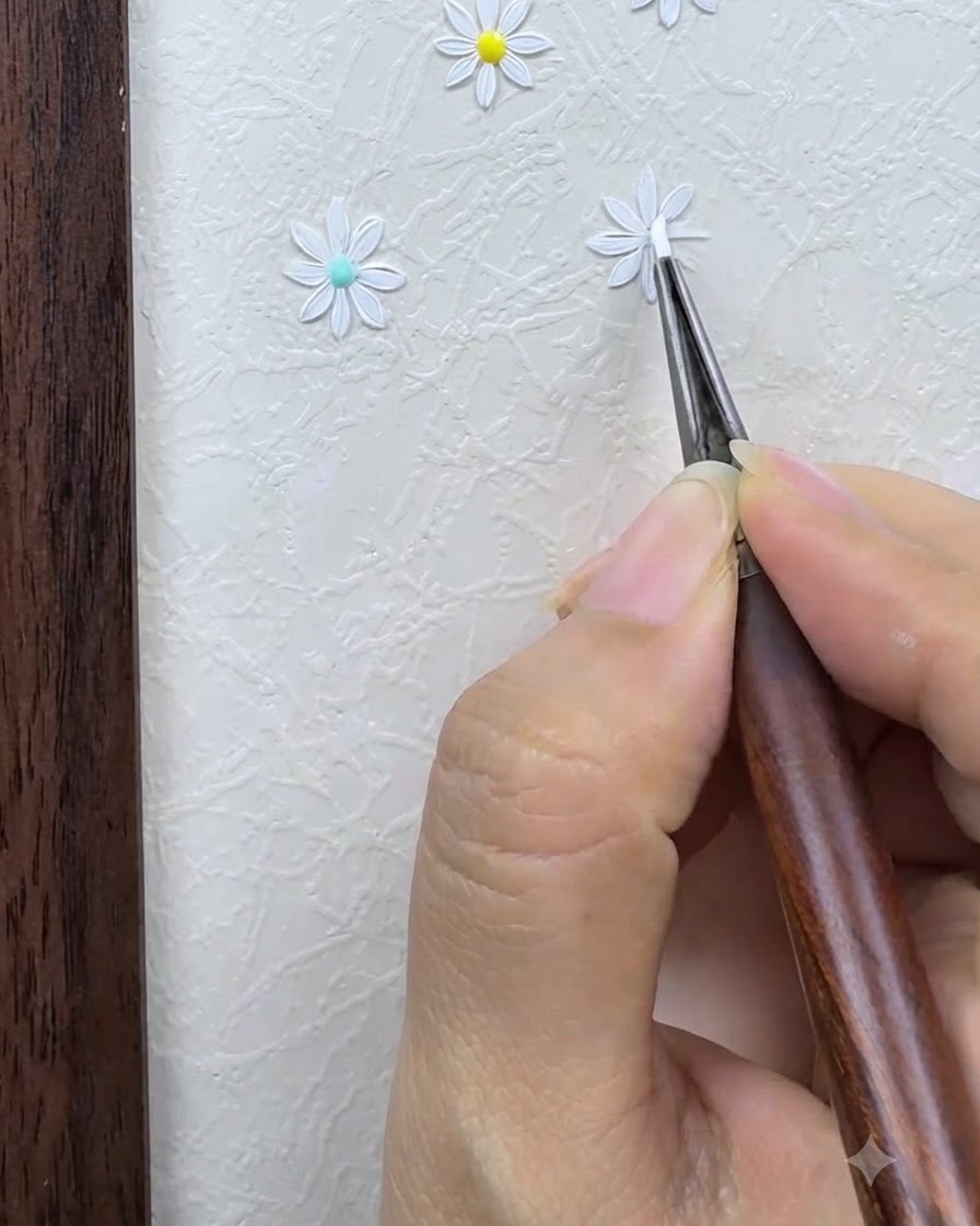 A detail brush carefully outlining and refining the white petals of a painted daisy on a textured nail art background.