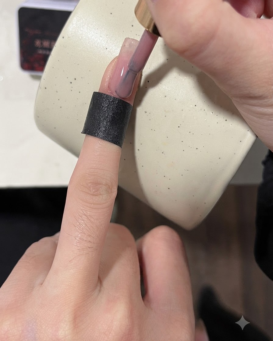 A brush applying a nude base coat to the surface of a practice nail plate.