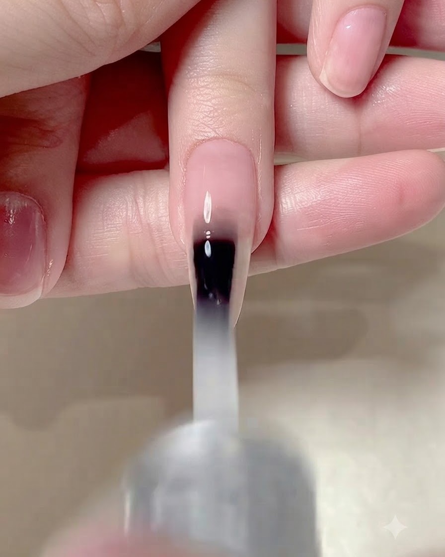 A nail brush applying a matte top coat over the entire surface of a manicured nail.