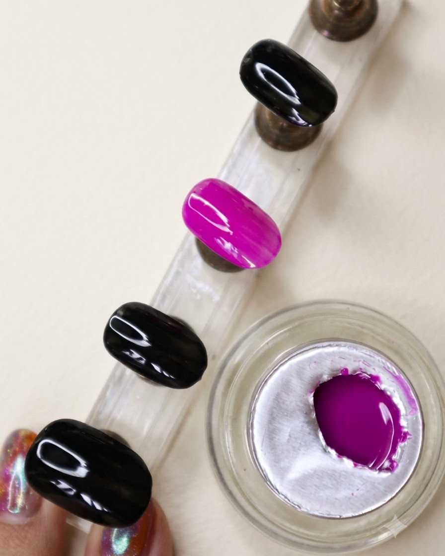 A display stand showing an accent nail with a fully opaque, vibrant neon purple finish.