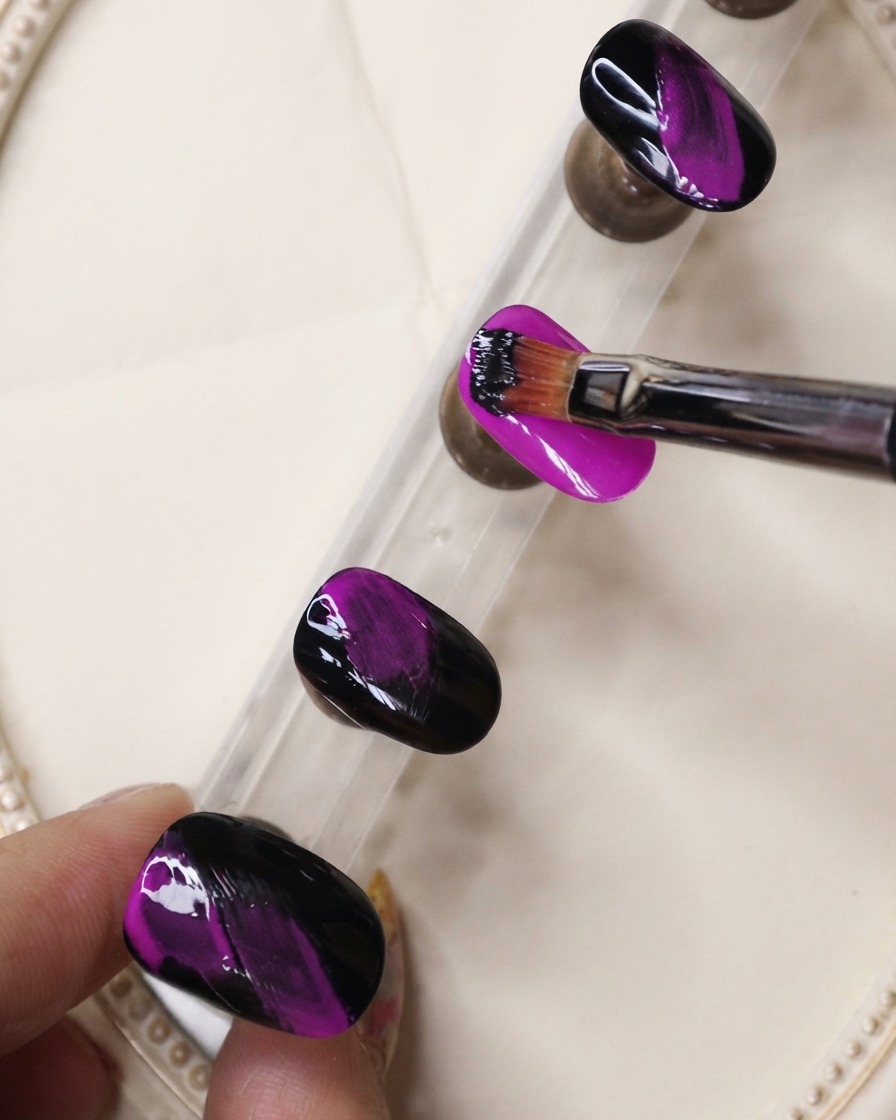 A fine liner brush applying black gel in textured strokes over a neon purple nail.