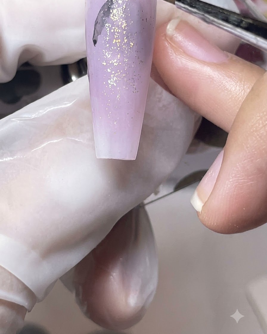 A fine liner brush drawing delicate black butterfly silhouettes onto a purple matte nail tip.