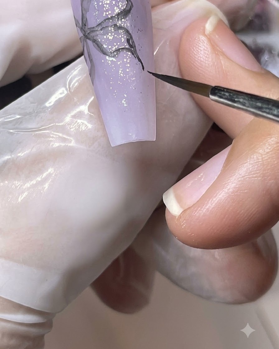 A fine brush blending and softening the black painted lines of a butterfly design with water.