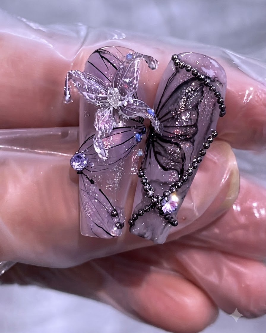Close-up of a finished set of purple butterfly and chain nail art designs on long clear nail tips.