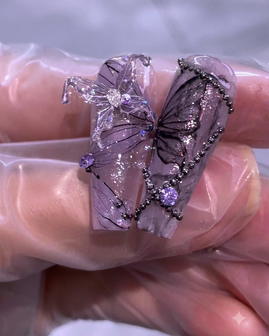 Close-up of completed purple and black nail art featuring butterfly details, rhinestones, and delicate thread lines.