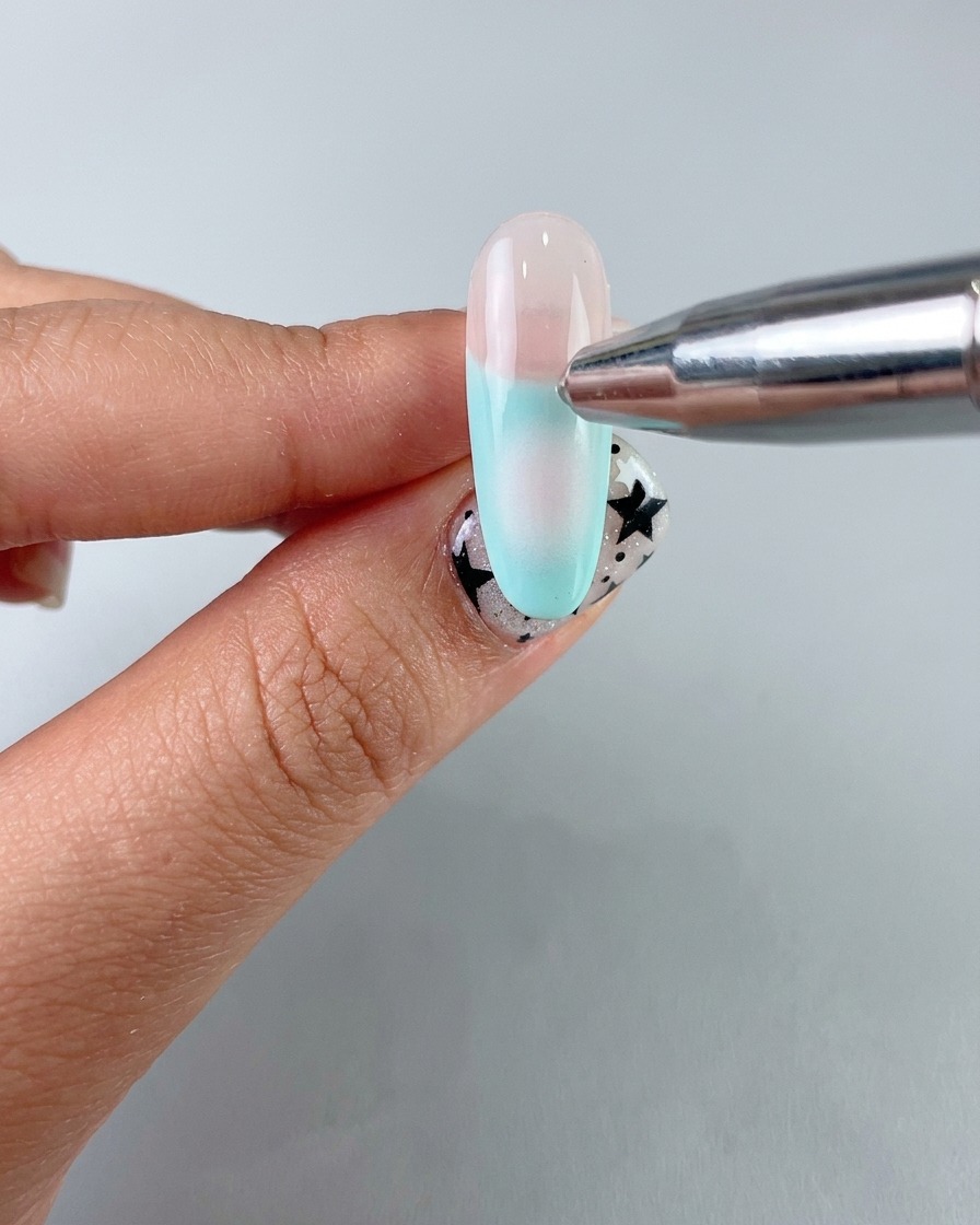 A sponge applicator applying a soft center blush gradient with gentle gel onto the nail.