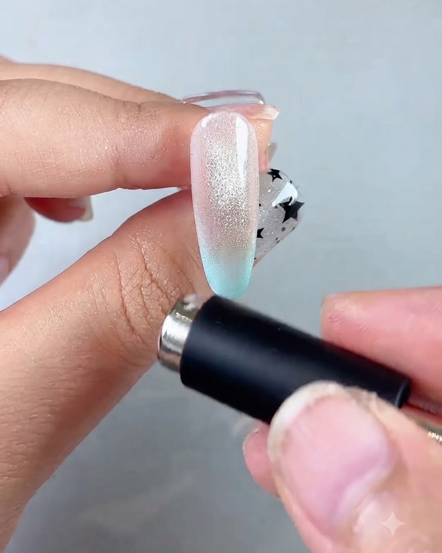 A magnetic wand circling the nail edge to form a concentrated glowing glass ball center.