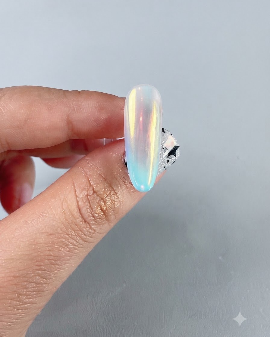 A close-up of a finished iridescent aurora chrome nail showing a vibrant multicolored mirror reflection.