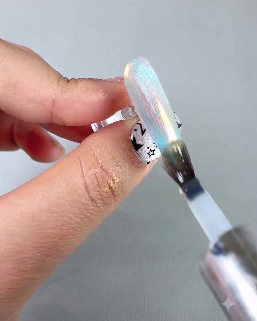 A nail brush applying a protective sealing top coat over an iridescent aurora chrome nail.