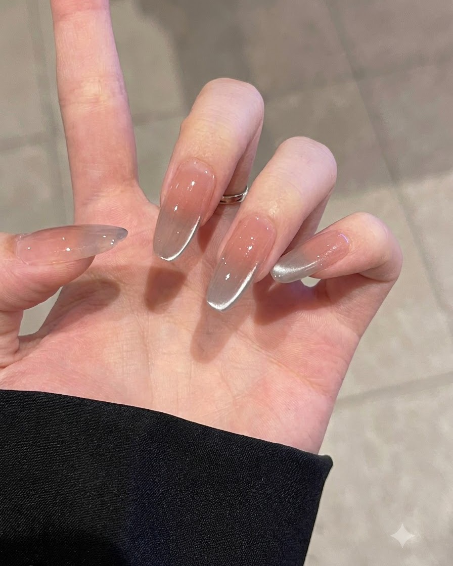 A hand using a pink sponge block to gently buff a clear practice nail tip.