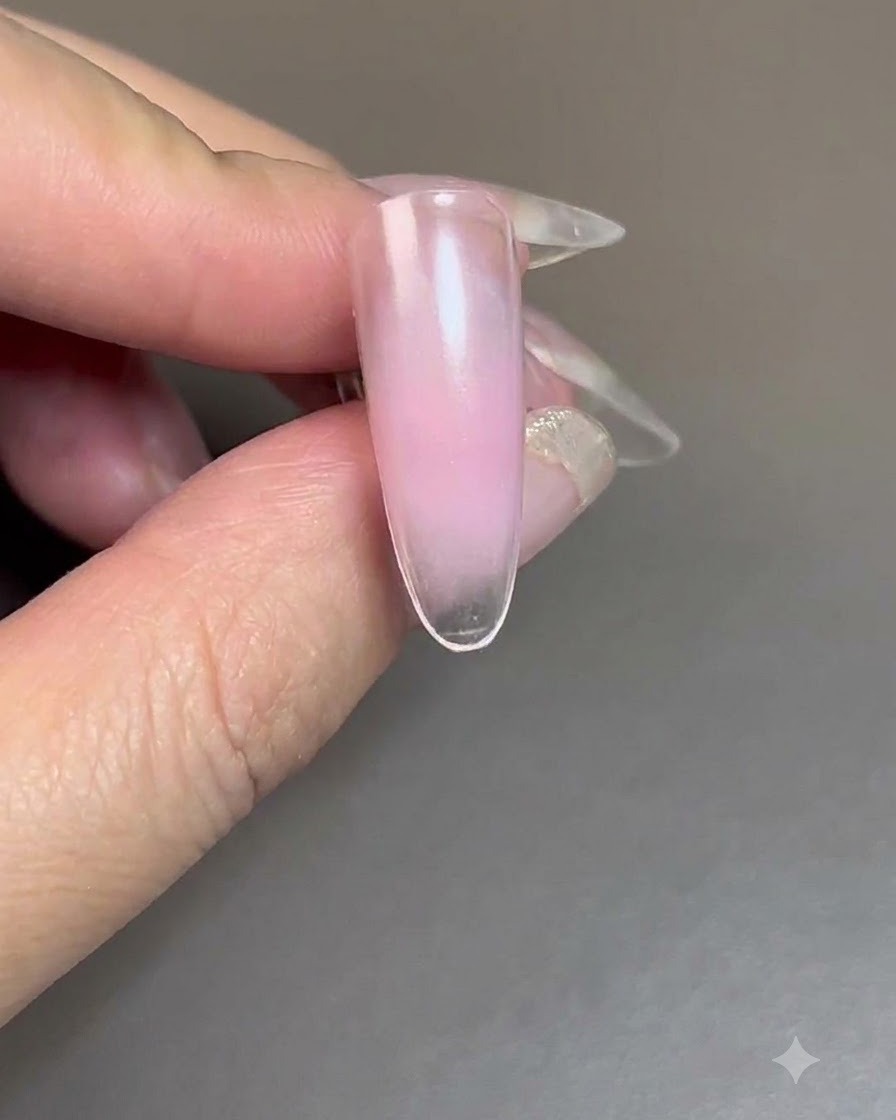 A nail with blush gel curing under a UV/LED nail lamp.