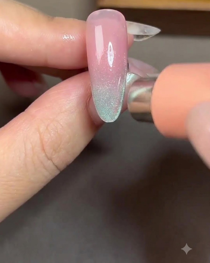 A magnet positioned on the right side of a nail to pull cat-eye particles into a bright side stripe.