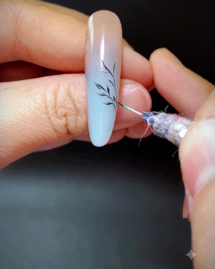 A fine liner brush painting delicate side branches on a gradient nail.