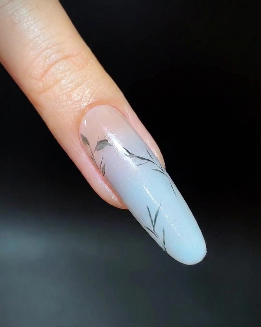 Close-up of a finger showing evenly spaced small green leaves painted on the upper nail branches.