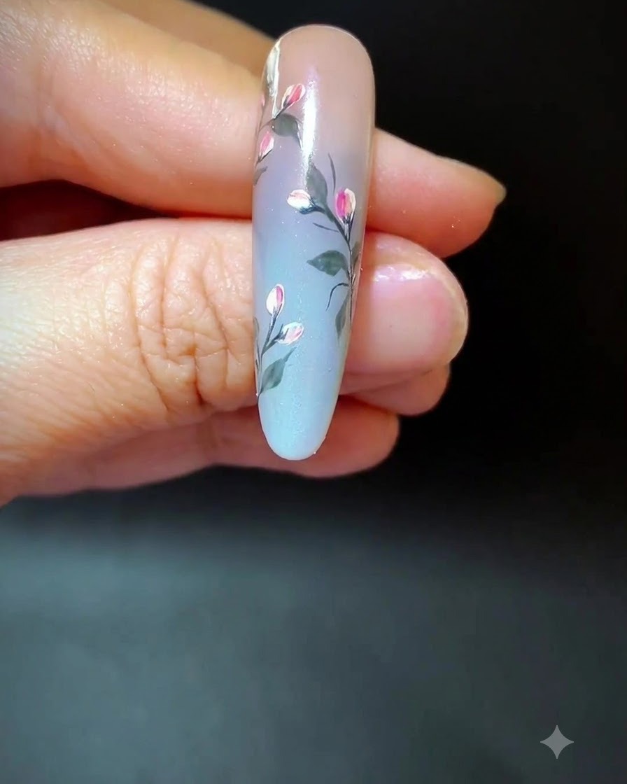 A nail showing completed floral art with added long wispy accent lines across the gradient space.