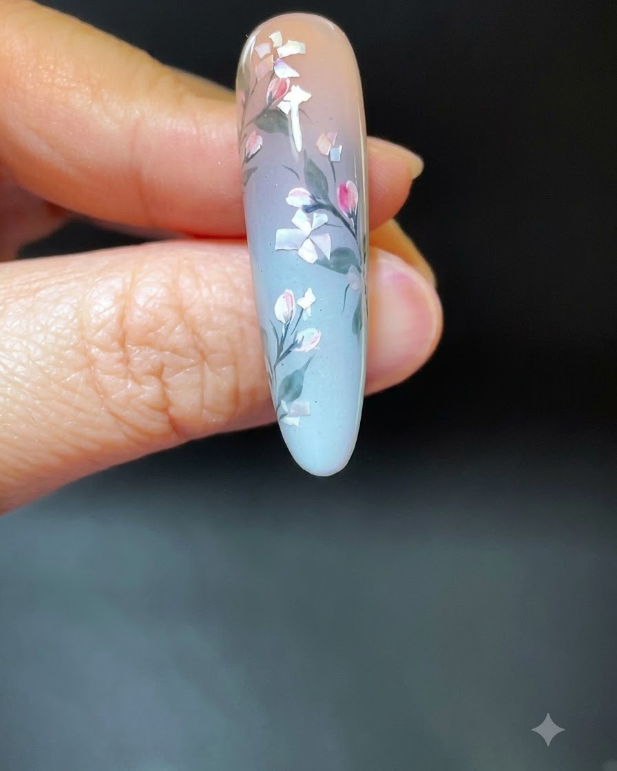A hand with finished shell floral nail art placed inside a white UV/LED curing lamp.