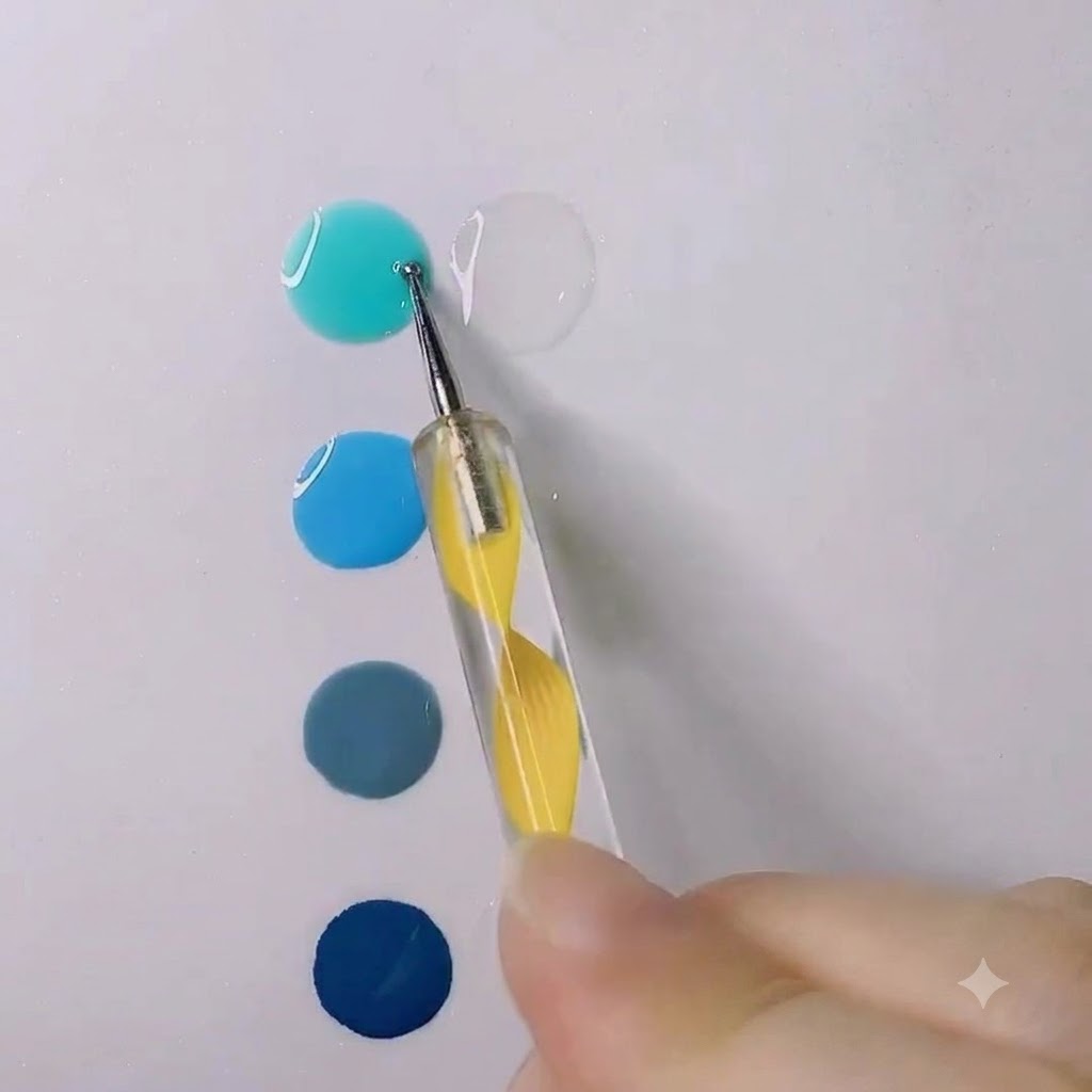 A dotting pen stirring a drop of bright water blue gel into a clear transparent gel drop on a white surface.