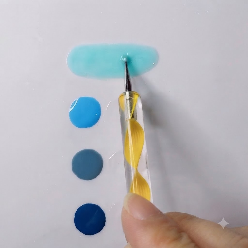 A dotting pen blending a vibrant sky blue gel with transparent gel into a smooth elongated puddle.