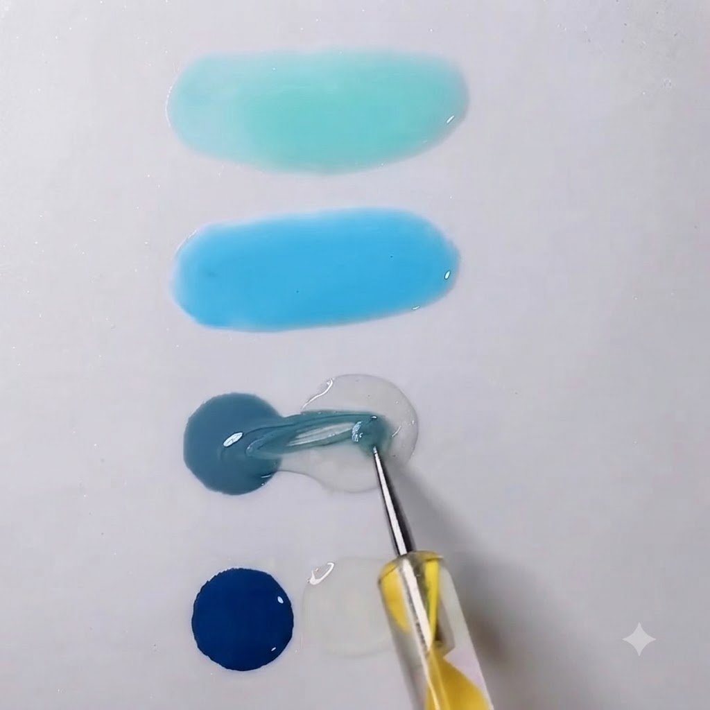 A mixing tool pulling grey gel into a neighboring drop of transparent gel on a white palette.