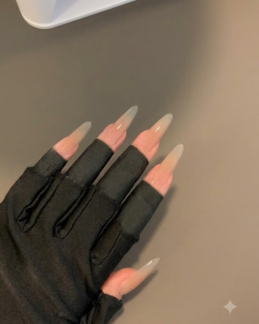 A gloved hand wearing black fingerless sleeves displaying the cured nails after 30 seconds under a lamp.