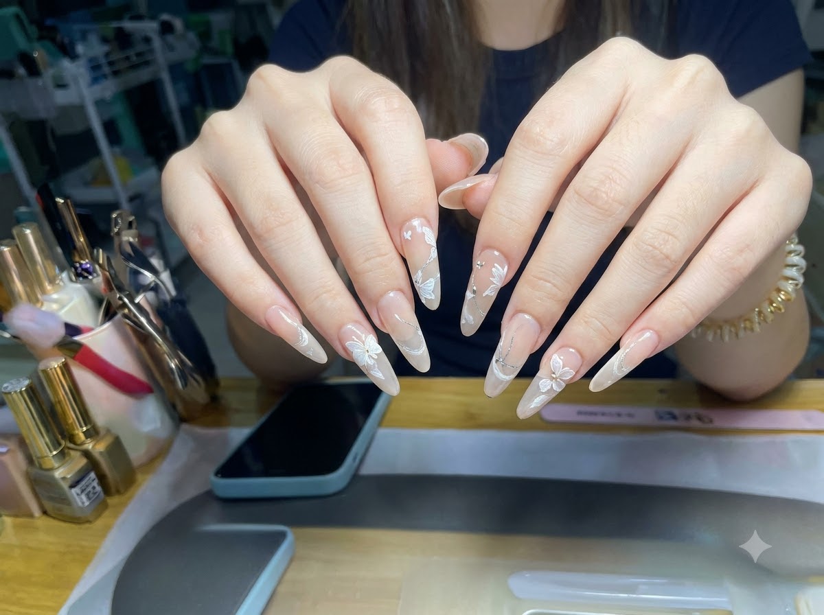 A macro-focused angle showing the glitter cat-eye layer and 3D floral designs on almond-shaped fingernails.