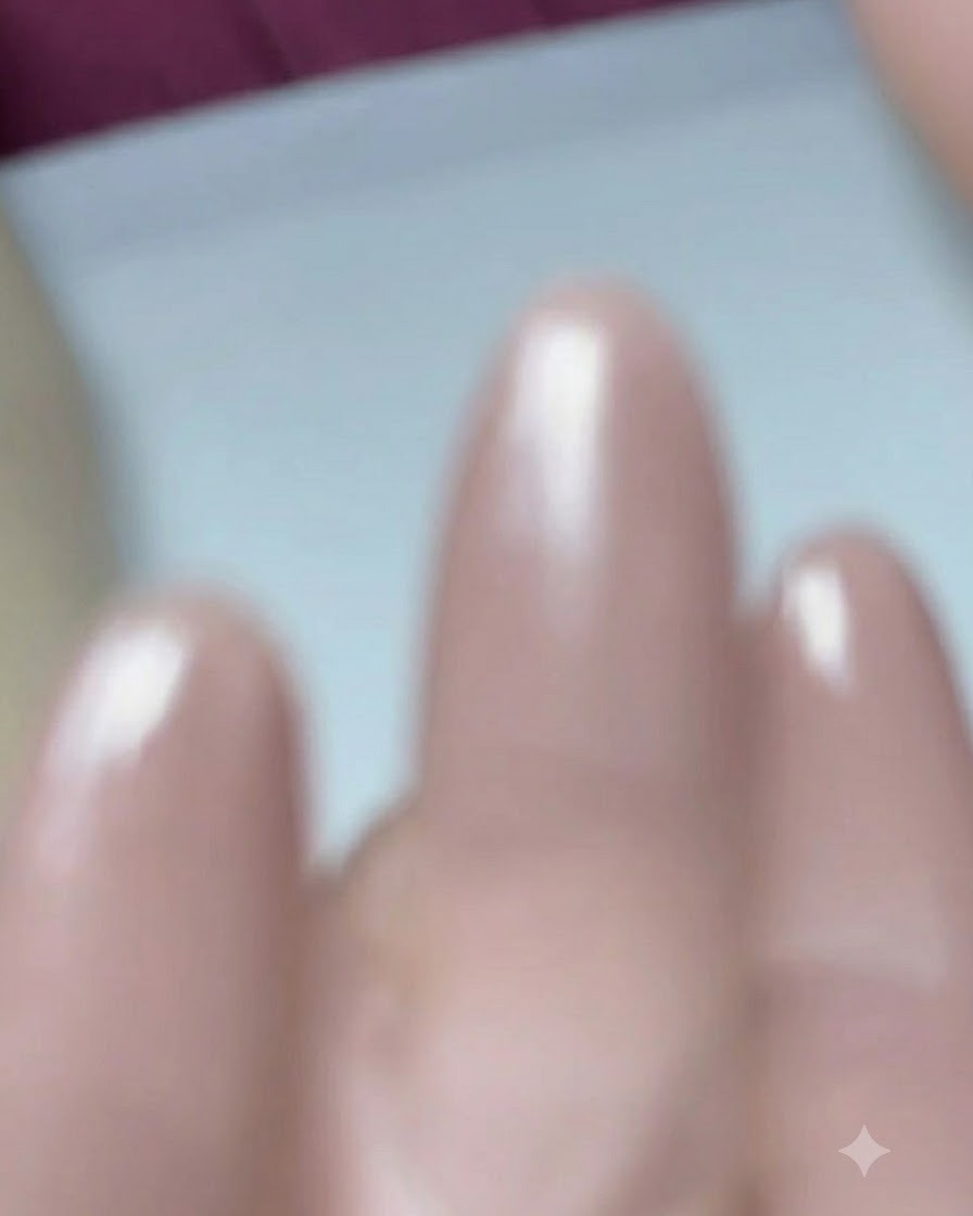 A close-up of a nail brush applying base coat gel onto a prepped almond-shaped nail.