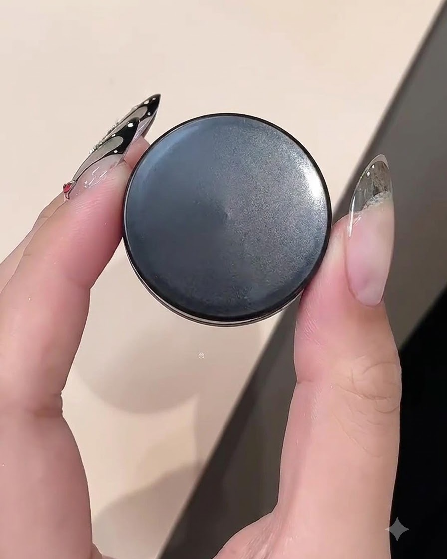 A close-up of a hand holding a jar of clay gel while working on a nail edge.